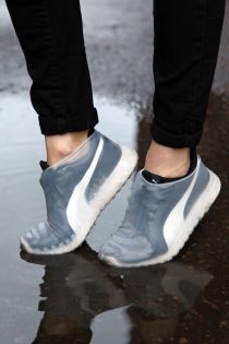 White waterproof shoe covers worn by a person on a wet street.